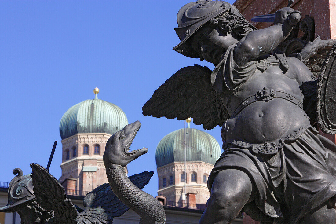 Dragon slayer, sculpture on the basement of the Mariensaeule, Frauenkirche in the background, Marienplatz, Munich, Bavaria, Germany
