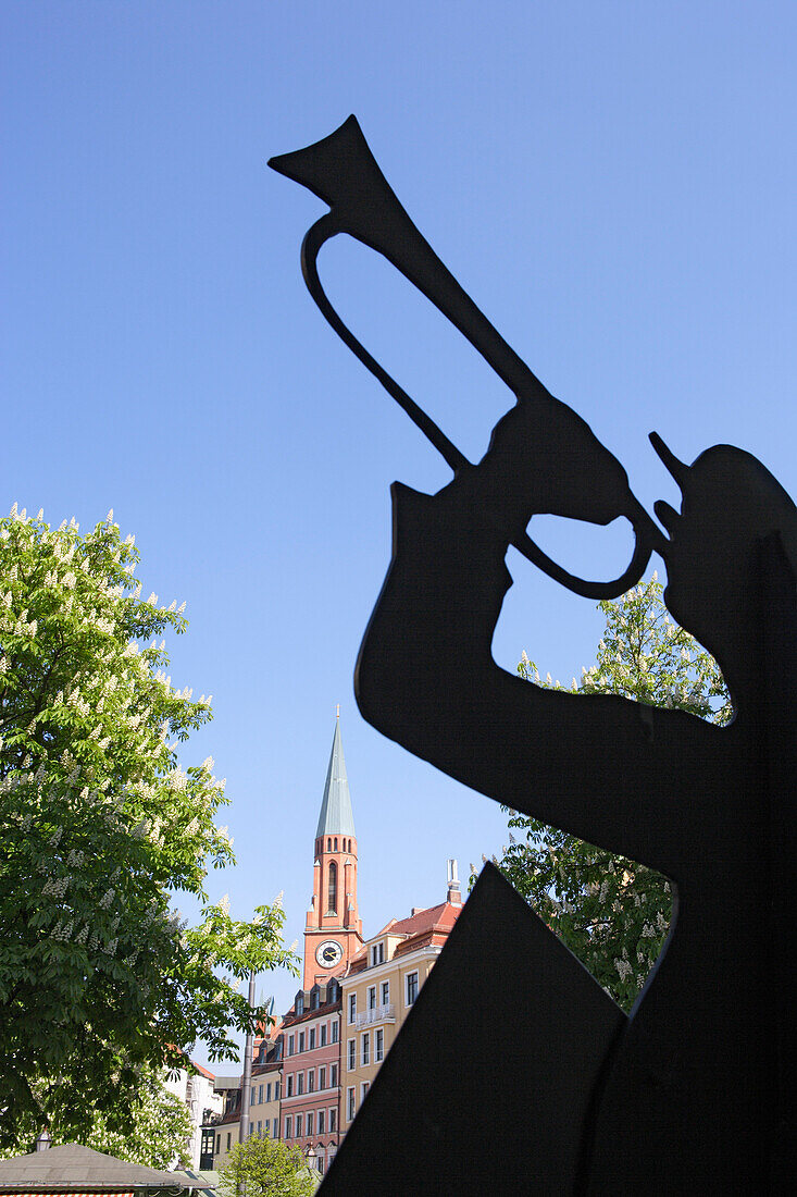 Figur des Karl Valentin mit dem Turm der Johanniskirche im Hintergrund, Haidhausen, München, Bayern, Deutschland