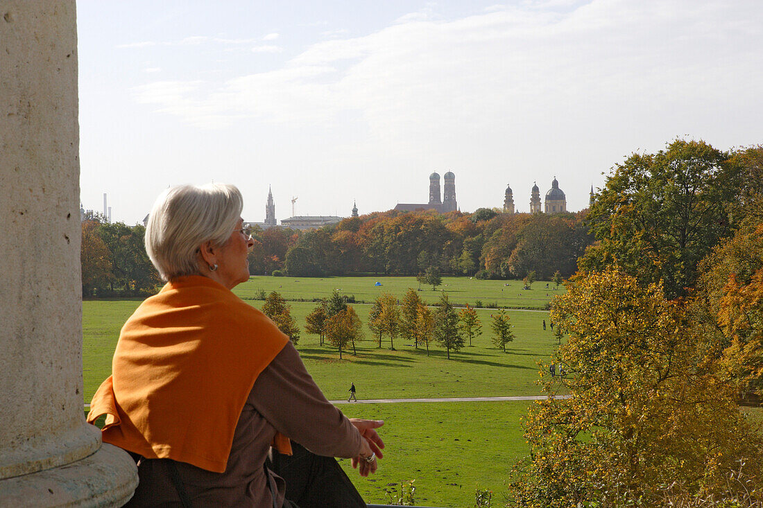 Frau blickt über den Englischen Garten und die Türme der Theatinerkirche und Frauenkirche, München, Bayern, Deutschland