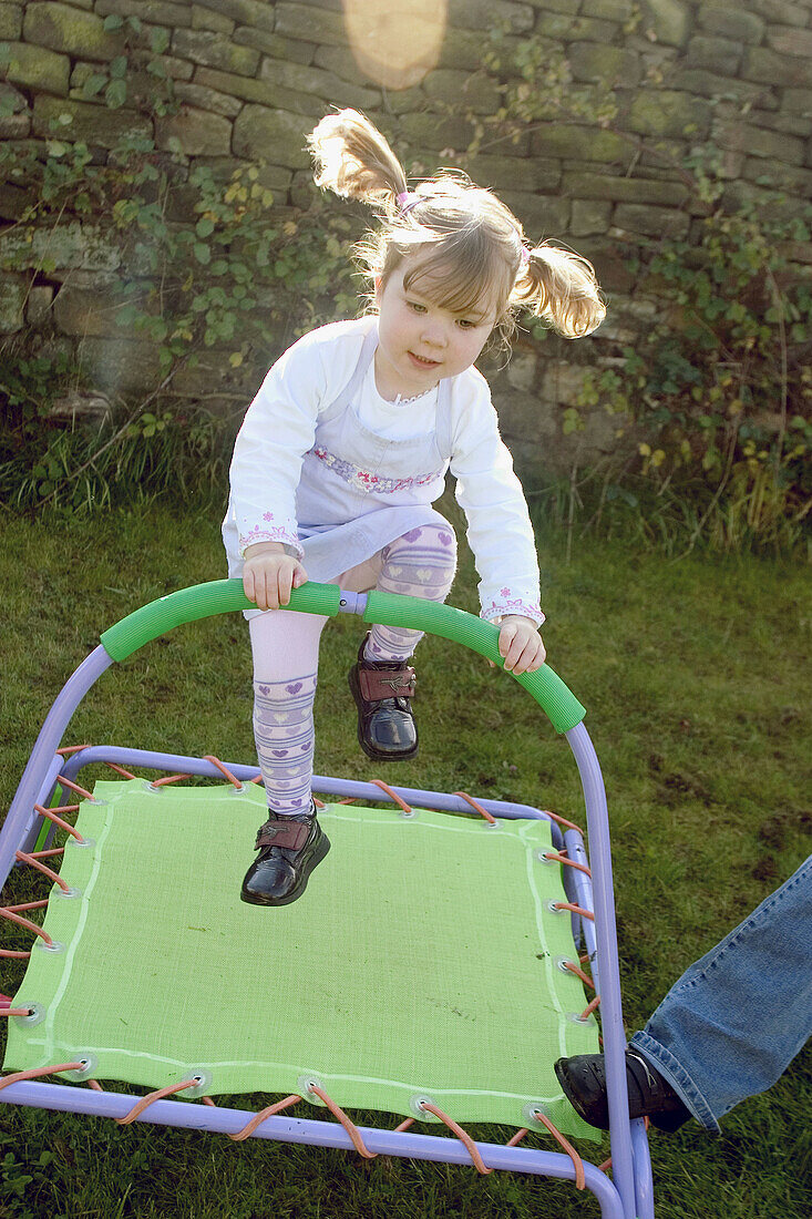 Three year old child jumping on a trampoline