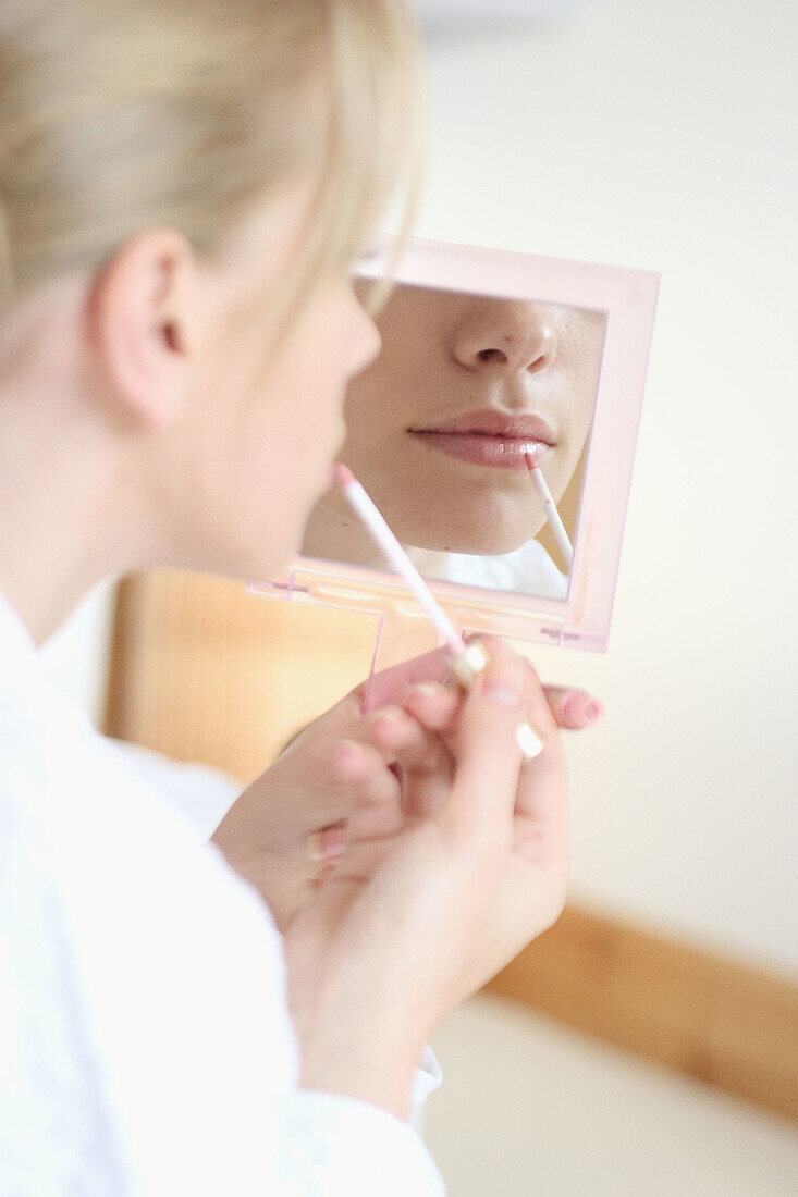 Close up shot of mouth of a girl putting lipstick on in a mirror