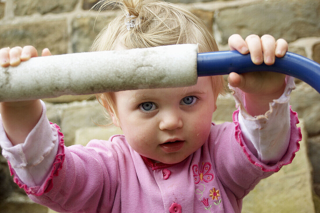 18 month old girl holding onto a trampoline, huge blue eyes