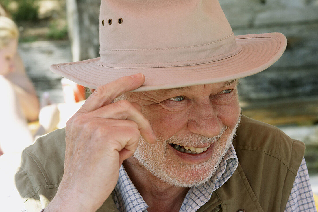 70 year old man outside in the sunshine wearing a hat, smiling off camera