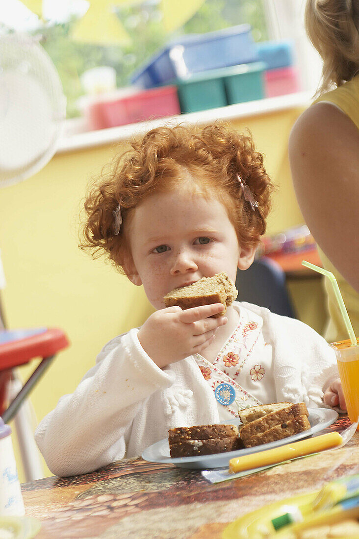 Red haired 3 year old girl, eating lunch.