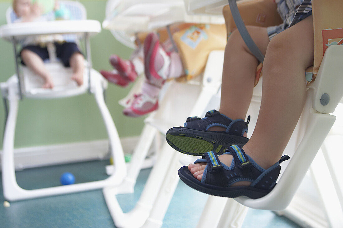Row of childrens feet in highchairs, at nursrey