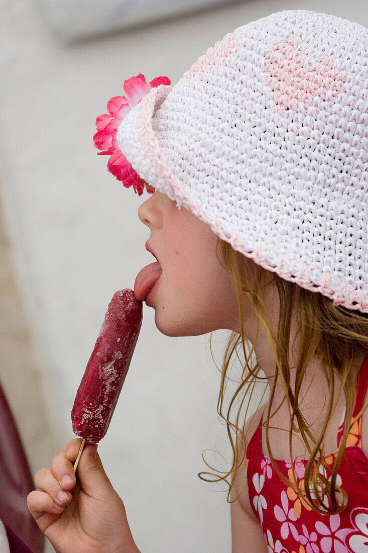 profile of a 4 year old girl licking a lolly