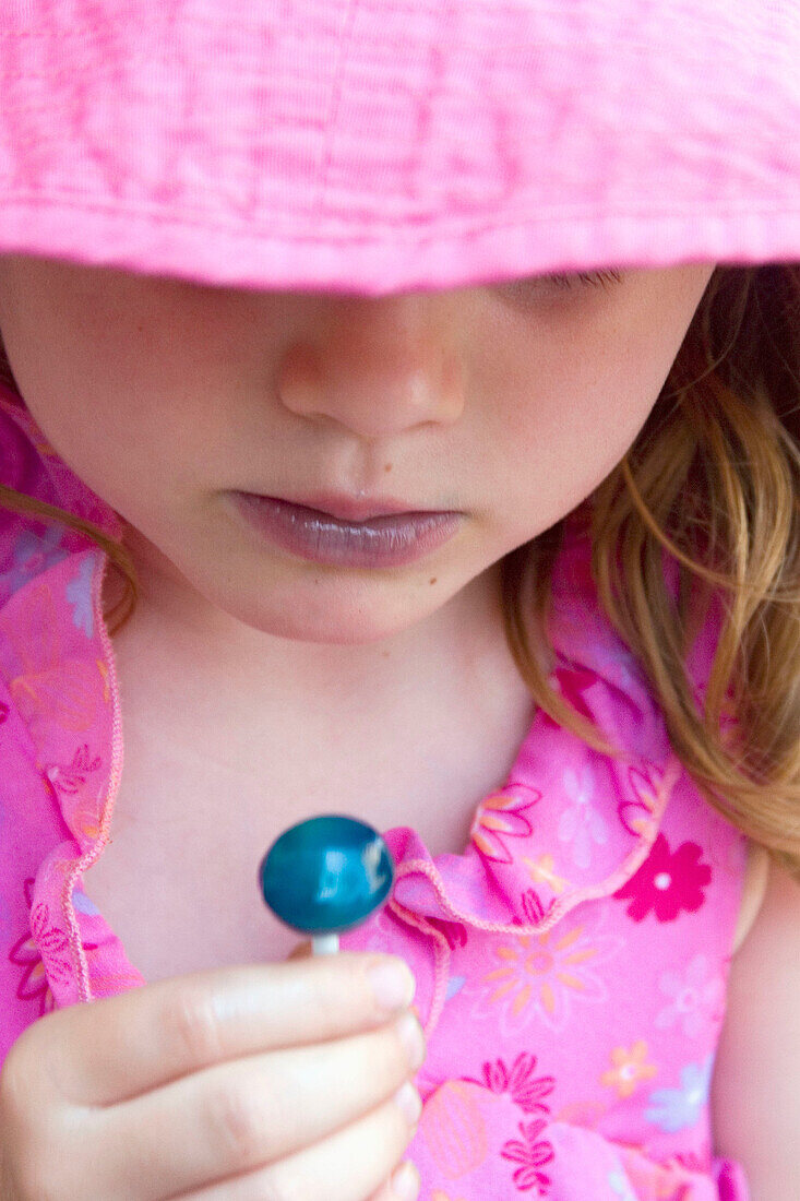 Headshot, 4 year old girl looking at a blue lolly