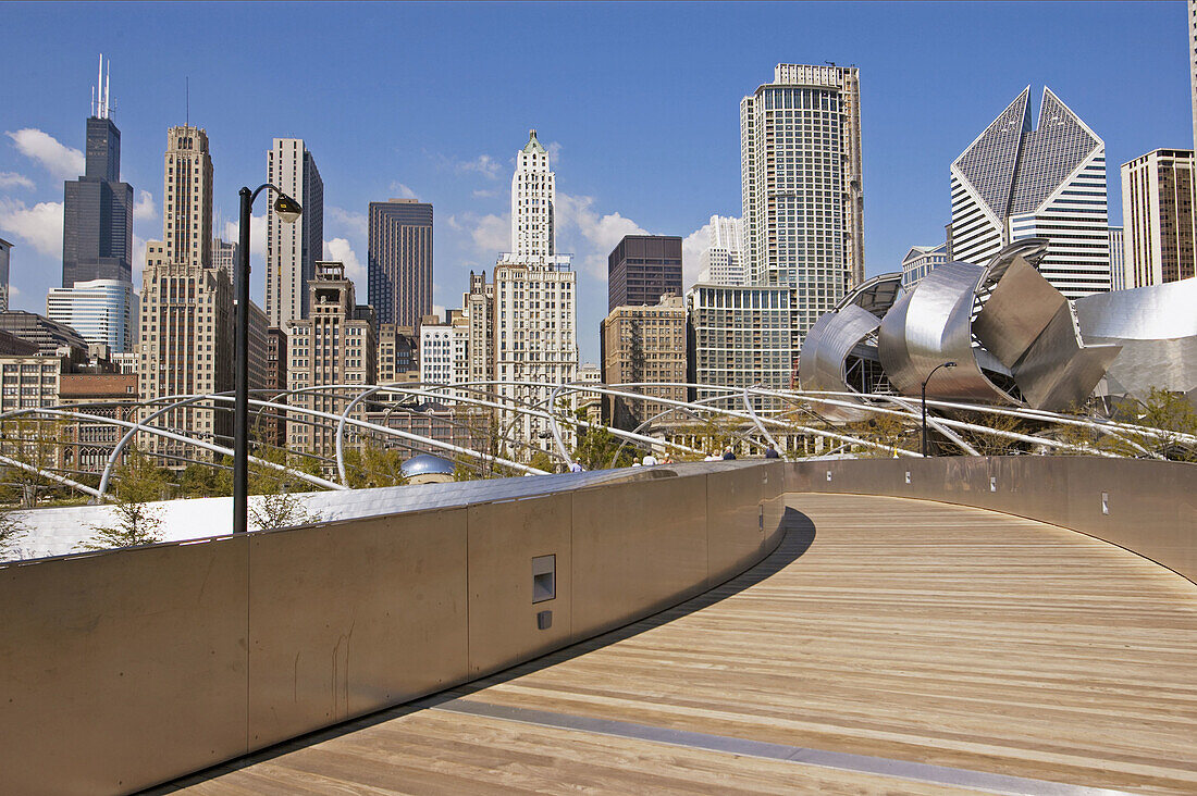 BP Bridge, Frank Gehry design, in Millennium Park, skyline, stainless steel curves, Pritzker Pavilion. Chicago. Illinois. USA