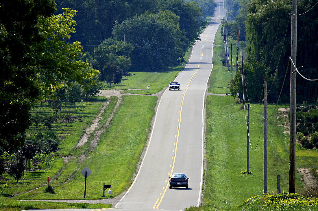 WISCONSIN. Kenosha County. Two land rural road through rolling hills, rural countryside in early fall, two vehicles on road