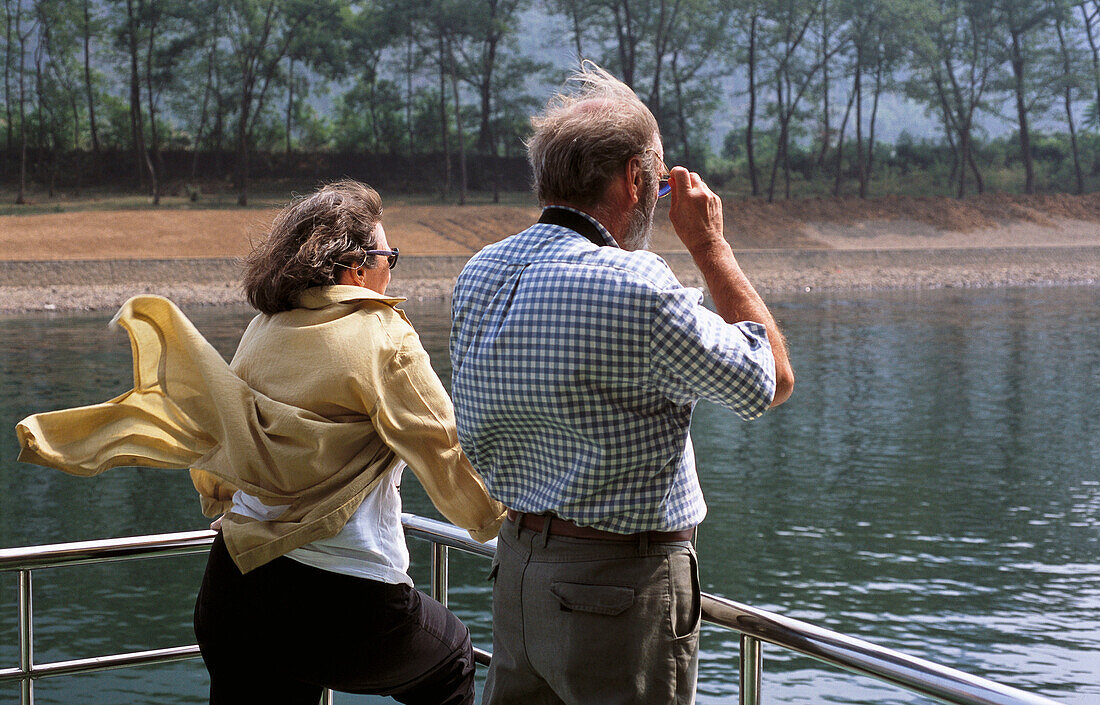 Tourist looking at mountains from boat on river, Guilin. China.