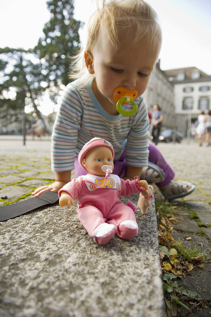 Baby girl playing with doll in the streets of Zürich, Switzerland.
