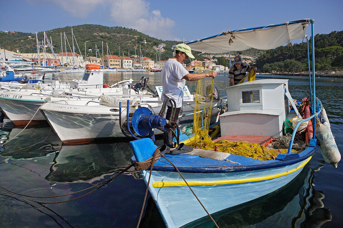 Zwei Männer arbeiten auf einem Boot im Hafen von Gaios, Paxos, Ionische Inseln, Griechenland