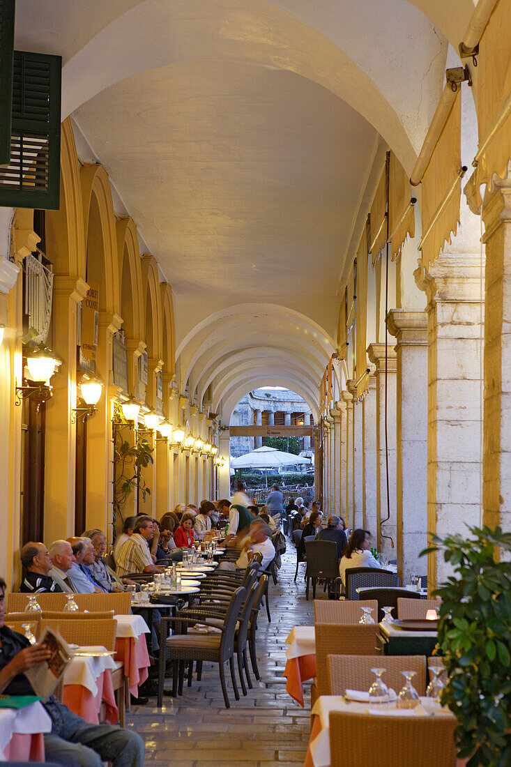 People sitting in cafes under the arcades of Liston, Corfu, Ionian Islands, Greece