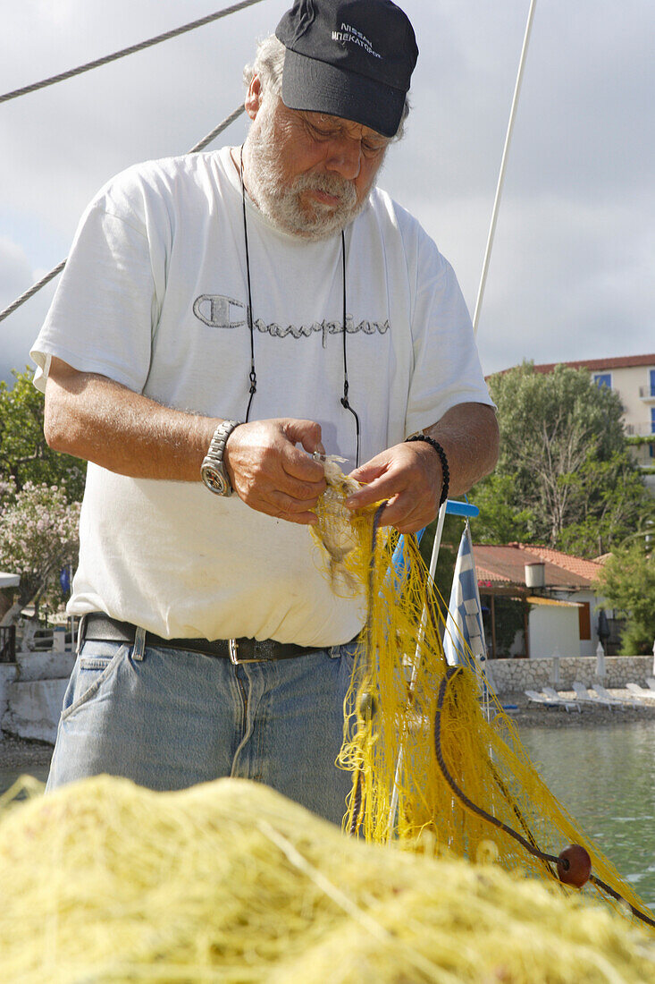 Kefalonia, ein Fischer aäubert sein Netz im Hafen Assos, Ionische Inseln, Griechenland