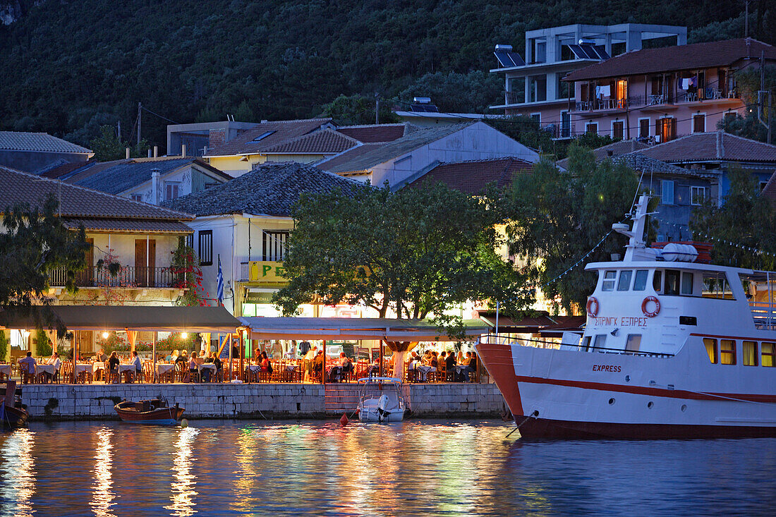 Menschen sitzen abends in einer Taverne am Hafen von Vasiliki, Lefkada, Ionische Inseln, Griechenland