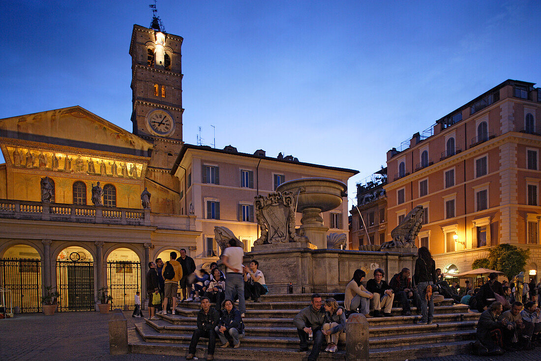 People sitting at a fountain at Piazza Sta Maria in the evening, Trastevere, Rome, Italy, Europe