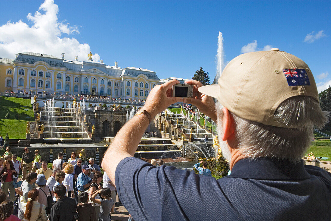 Man taking a photograph of the Grand Cascade in the park of Peterhof Palace, St. Petersburg, Russia