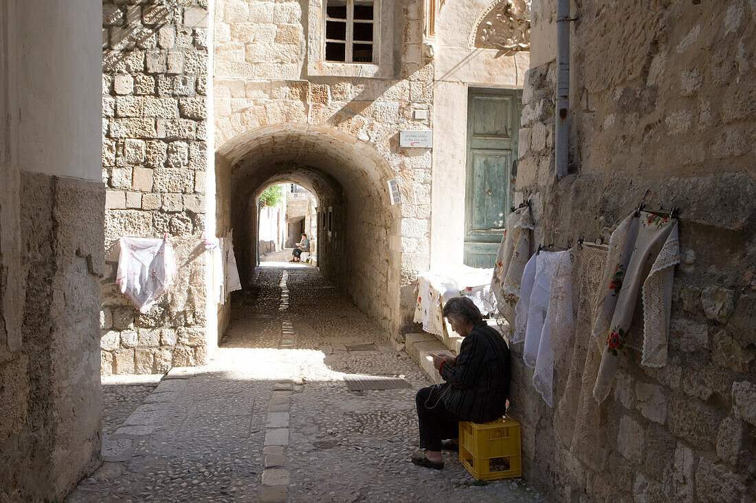Frau verkauft geklöppeltes Handwerk in Gasse von Altstadt, Dubrovnik, Dalmatien, Kroatien, Europa