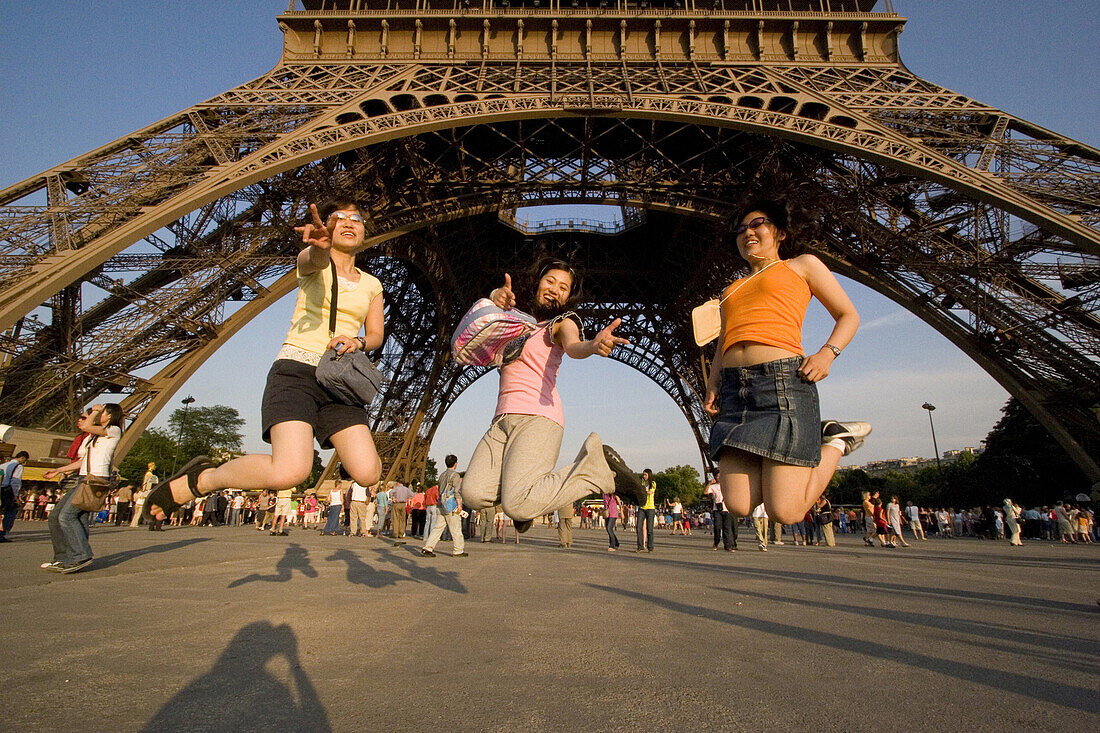 Japanische Mädchen hüpfen vor dem Eiffelturm, Paris, Frankreich, Europa