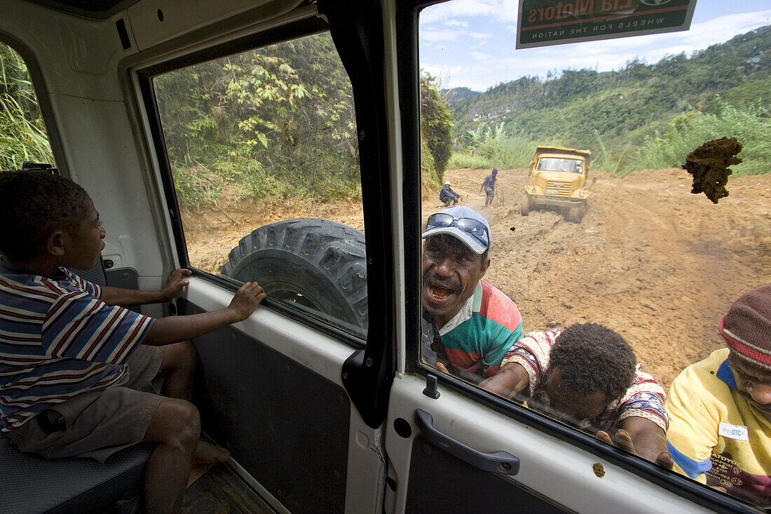 Auto steckt im Schlamm und wird von Einheimischen geschoben, Bulolo, Papua Neuguinea, Ozeanien
