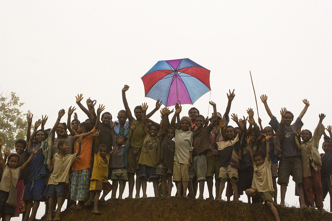 Eine Gruppe jubelnder Kinder mit Regenschirm, Langila, Papua Neuguinea, Ozeanien