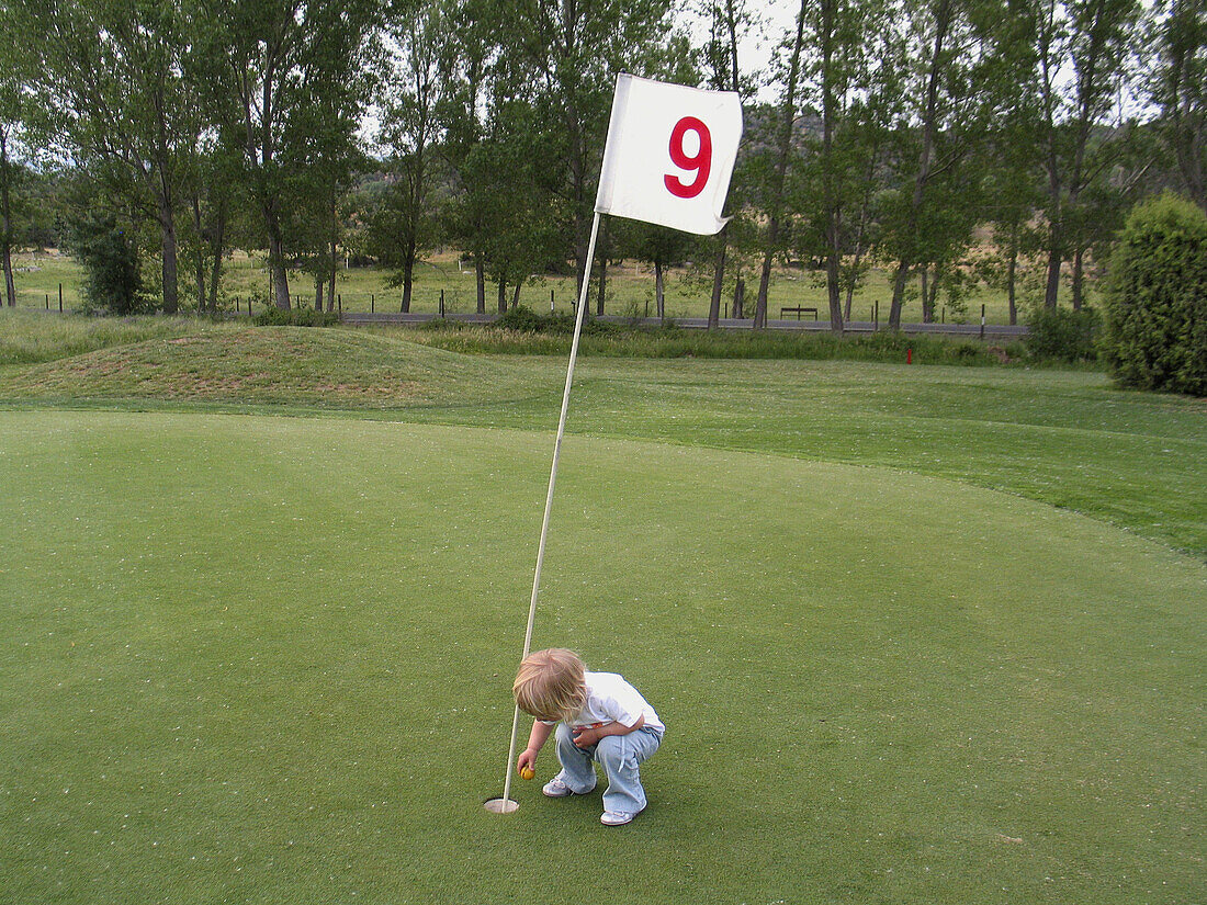  1 to 2 years, 1-2 years, Child, Children, Color, Colour, Concept, Concepts, Crouch, Crouching, Daytime, Detail, Details, Exterior, Flag, Flags, Golf, Golf course, Golf courses, Green, Hole, Holes, Infant, Infants, Kid, Kids, Number, Number 9, Number nine