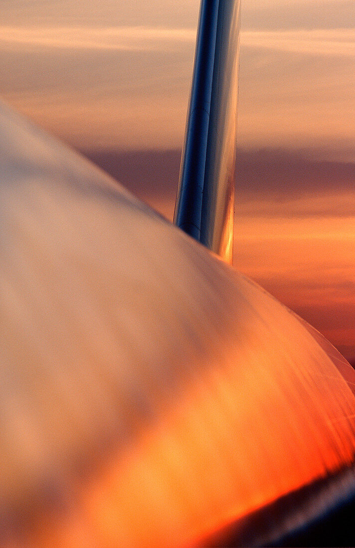 View along aircraft fuselage reflecting red & gold sunset sky