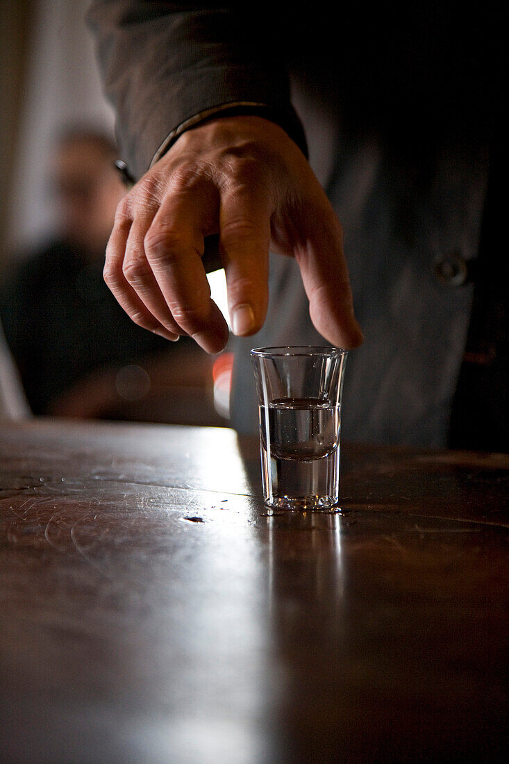 Man holding Grappa glass in Nardini Grappa Bar, Bassano del Grappa, Veneto, Italy