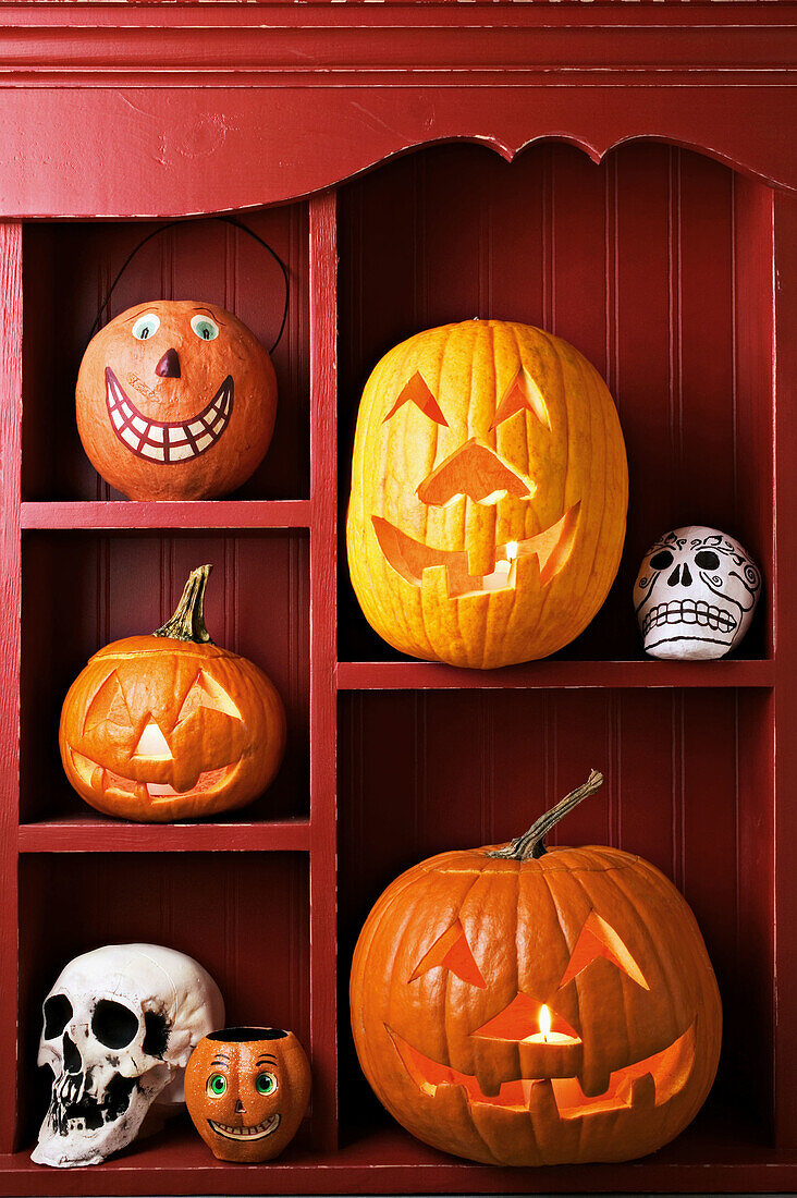 An old red cabinet with Halloween items, carved pumpkins, skulls