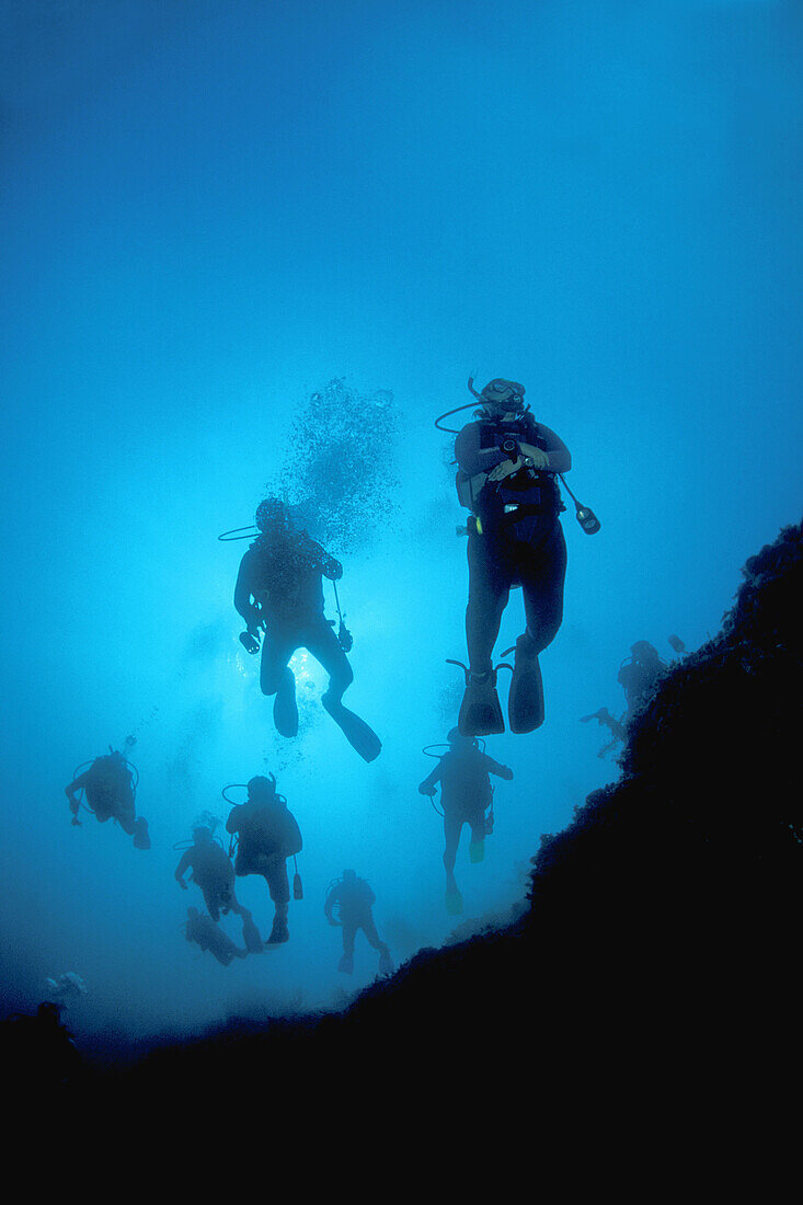 View looking back at a train of divers descending down the Blue Hole, Lighthouse Reef Atoll, Belize, Caribbean Sea