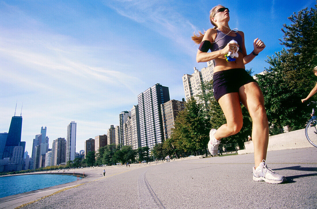 Junge Frau joggt am Morgen an der Goldküste, Gold Coast, Oak Street Beach, Chicago, Illinois, USA