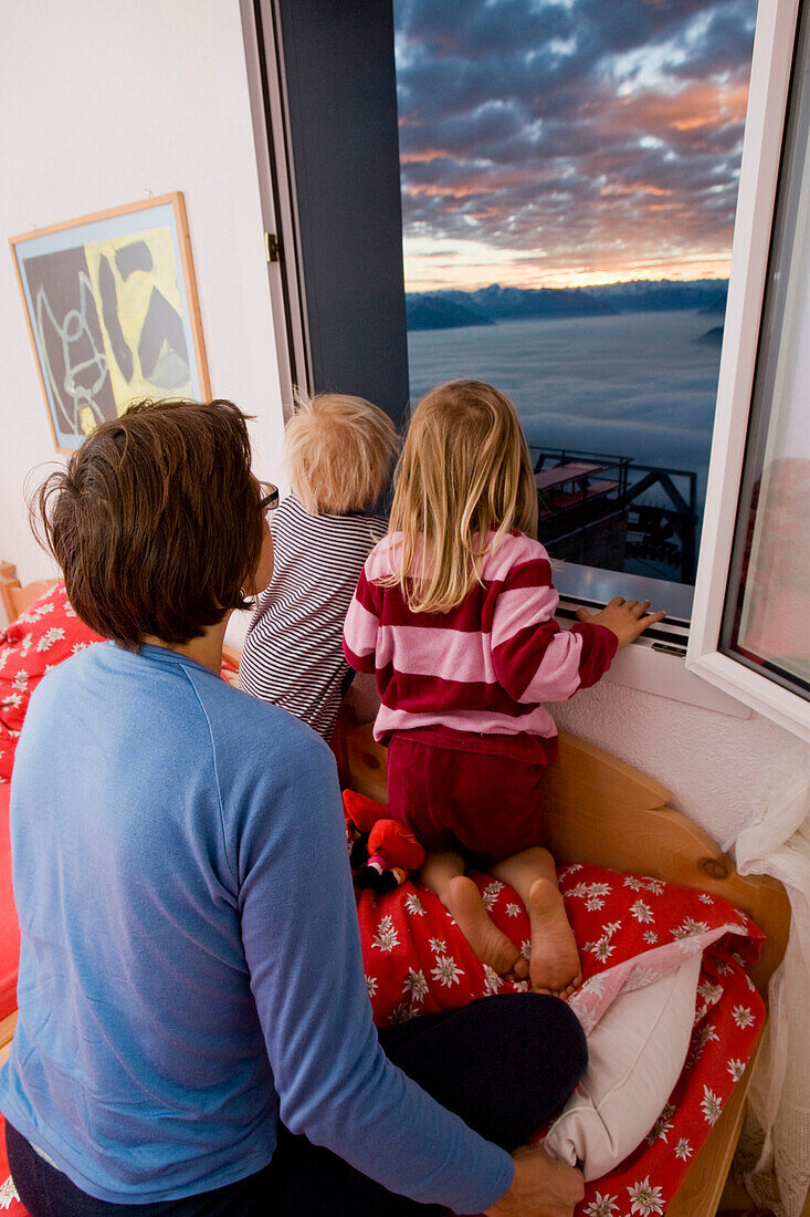 Mother and childern whatch the mornig mood through window, Alpstein, Canton of St. Gallen, Switzerland