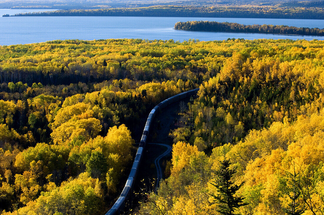 Aspen forest in autumn colour overlooking Lake Superior with rail line and train. Rossport. Ontario