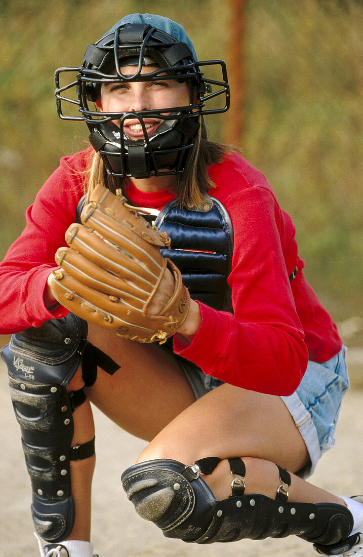 Young female baseball catcher playing game on field