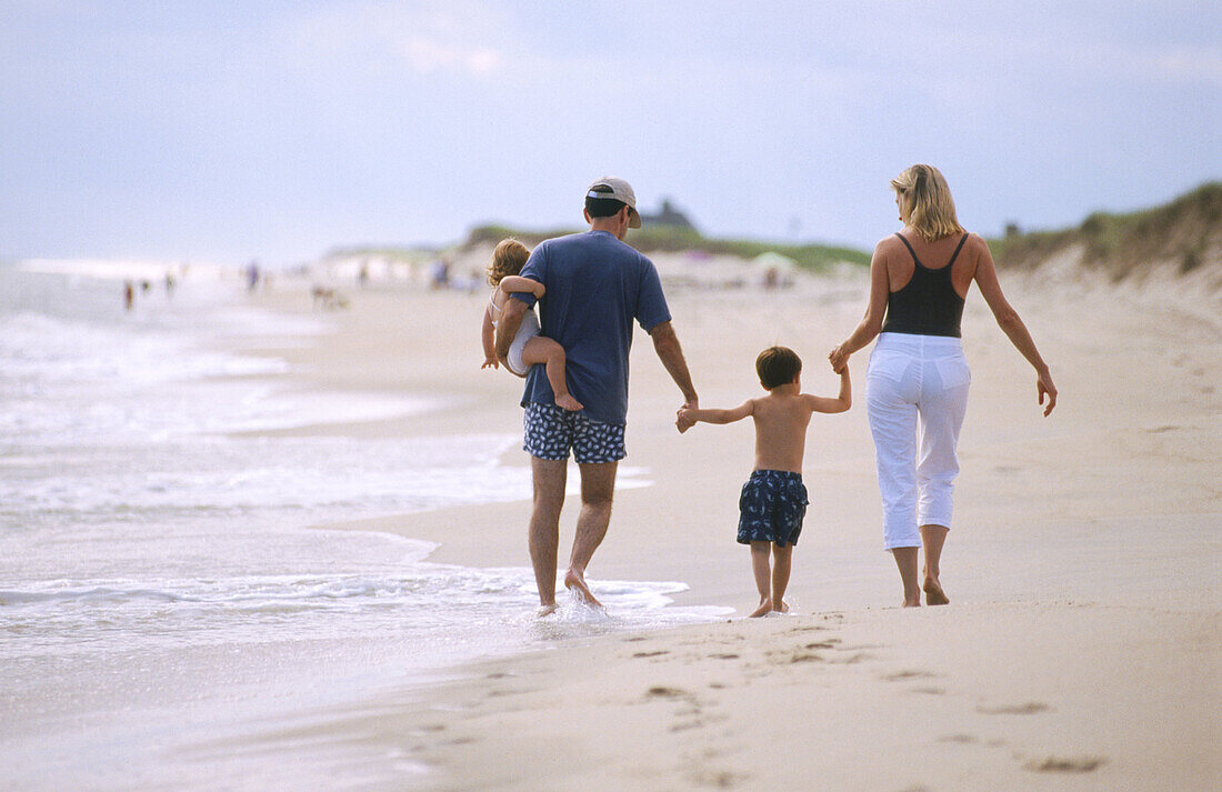 Family on beach. Parents with son and daughter leaving footprints in the sand, nuclear family, Nantucket, Massachusetts , USA
