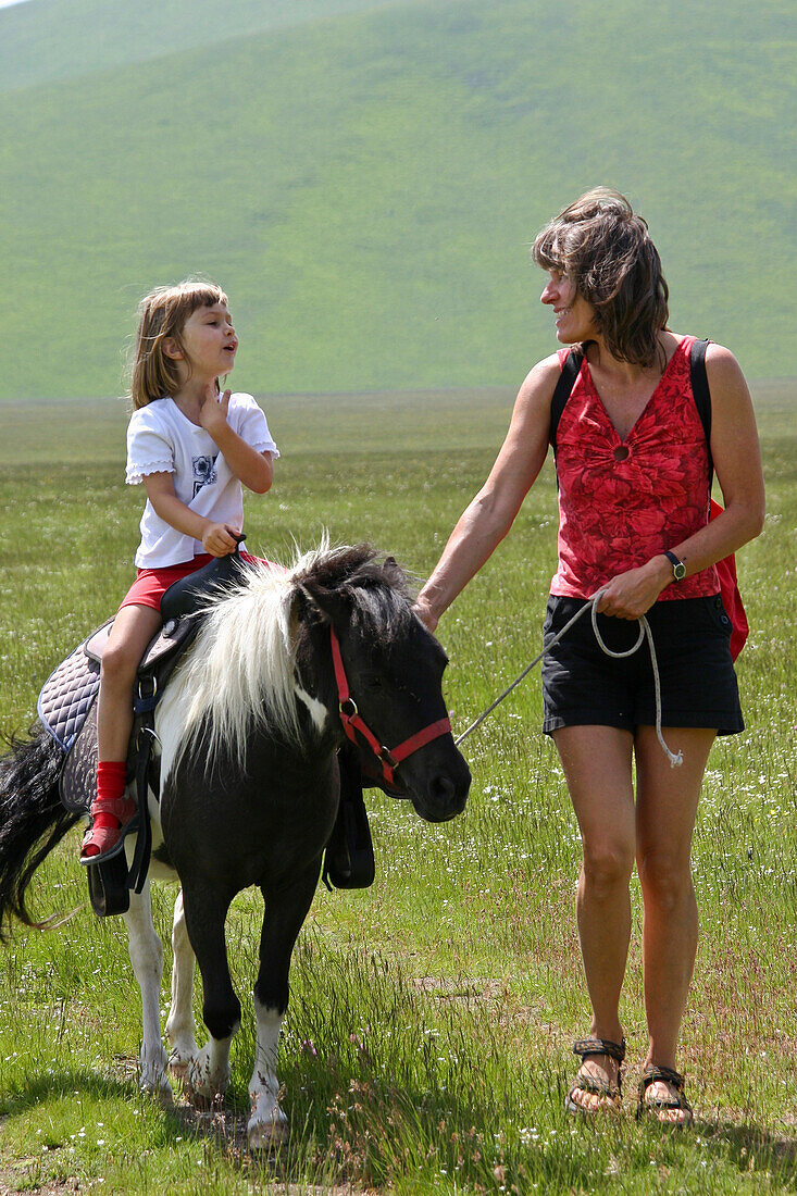 Mother and daughter with pony, girl riding pony, Umbria, Italy