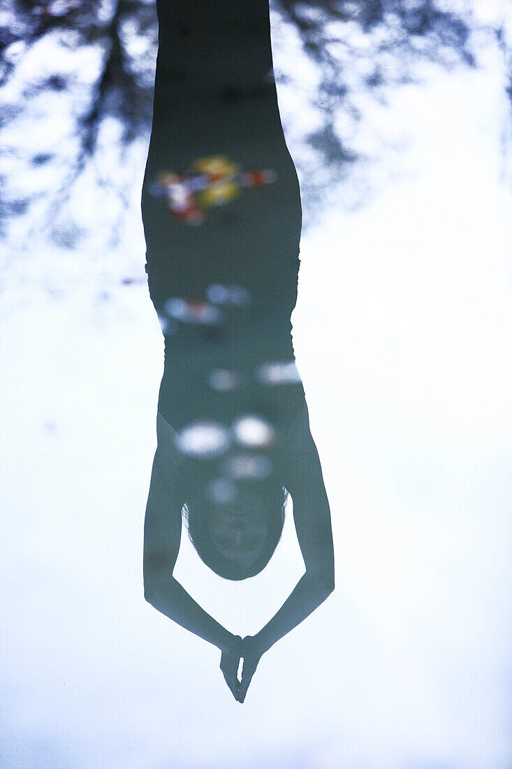 Reflection of a young woman in the water doing yoga, Kaufbeuren, Bavaria, Germany