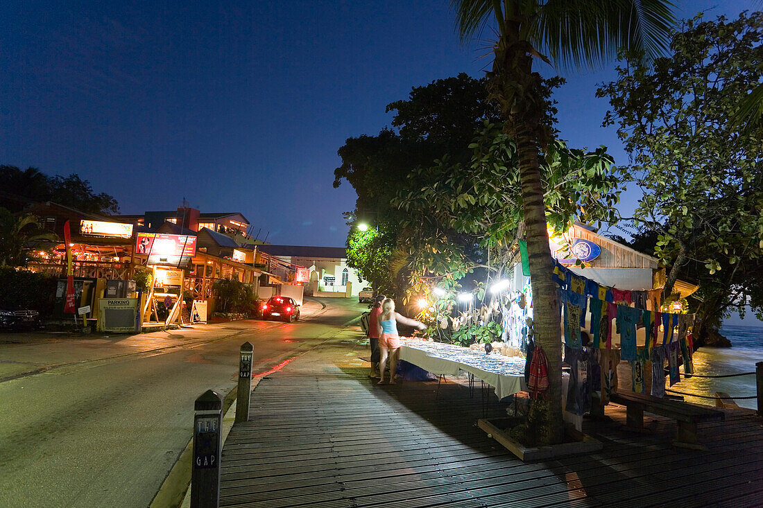 Tourists at souvenir stand at night, St. Lawrence Gap, Barbados, Caribbean