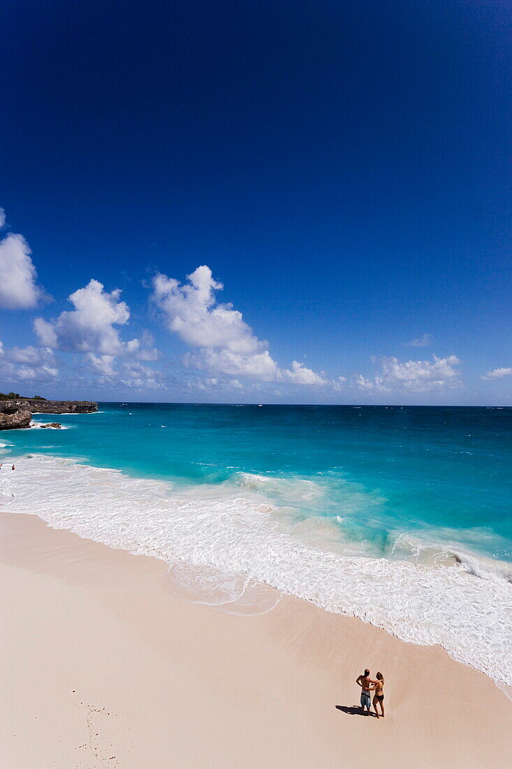 Couple standing in spray of Atlantic Ocean at Bottom Bay, St. Philip, Barbados, Caribbean