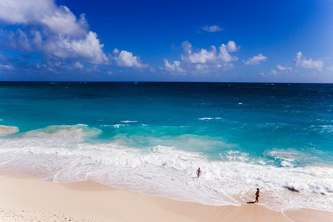 Couple standing in spray of Atlantic Ocean at Bottom Bay, St. Philip, Barbados, Caribbean