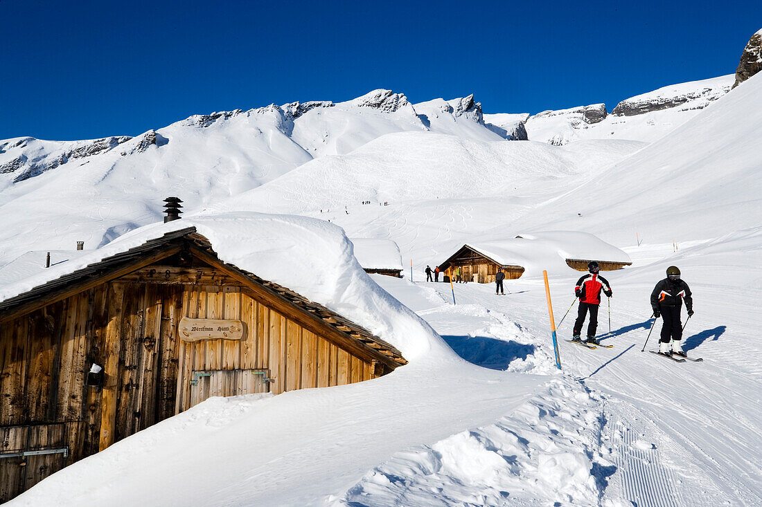 Skiers on slope passing alpine hut, First, Grindelwald, Bernese Oberland, Canton of Bern, Switzerland