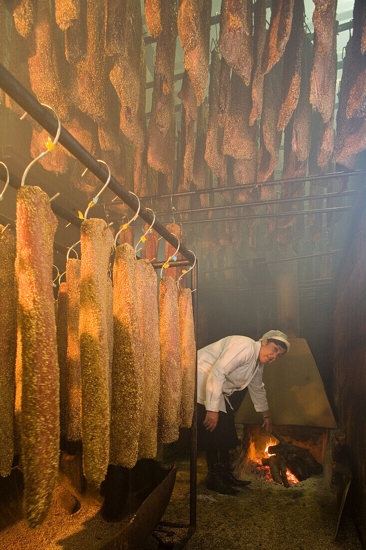 Woman inside the smokehouse, Sausages and smoked ham hung up in the smokehouse, Kafkalia Ltd., Agros, Pitsilia region, Troodos mountains, South Cyprus, Cyprus