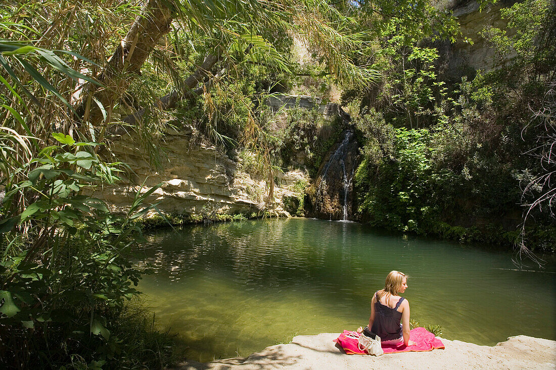 Junge Frau sitzt auf Felsen, Adonis Baths, Adonis Bad, Coral Bay, Paphos, Südzypern, Zypern