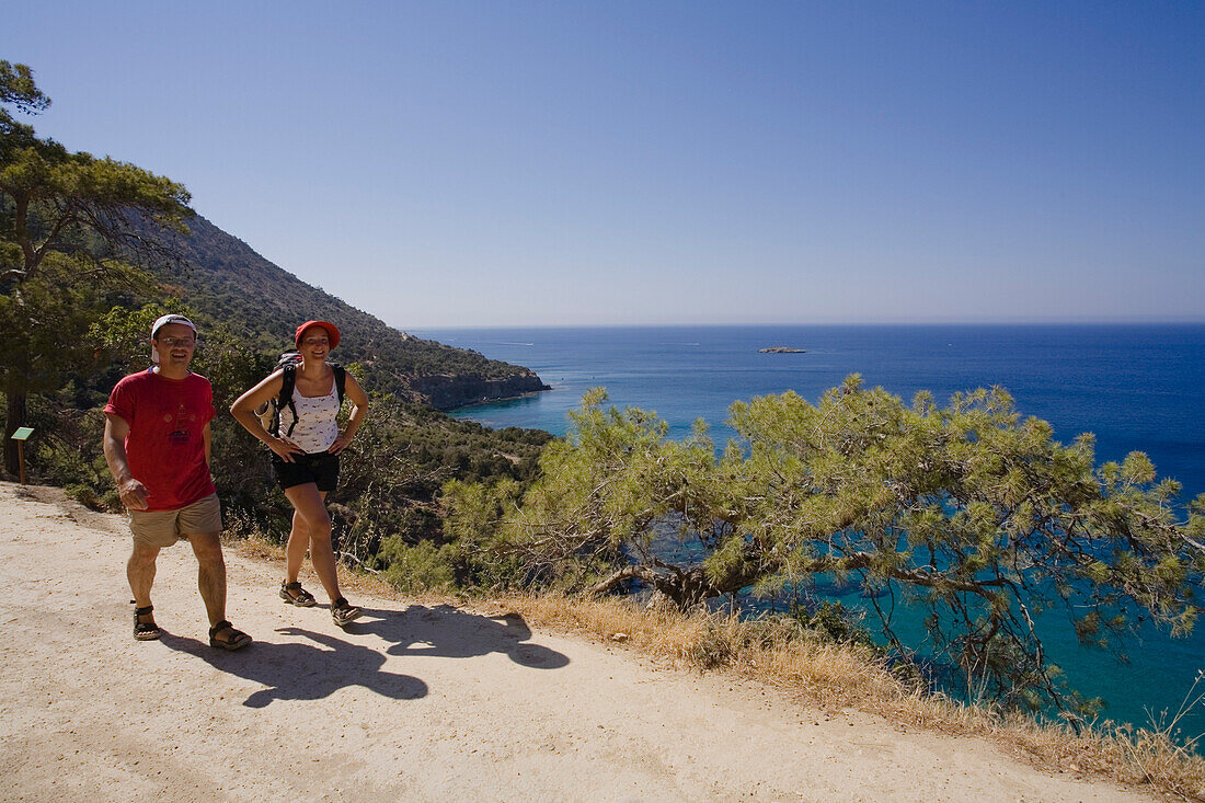 Ein Paar beim Wandern entlang der Küste, Küstenlandschaft mit Kiefer, Akamas Naturpark, türkis blauen Meer, South Cyprus, Cyprus