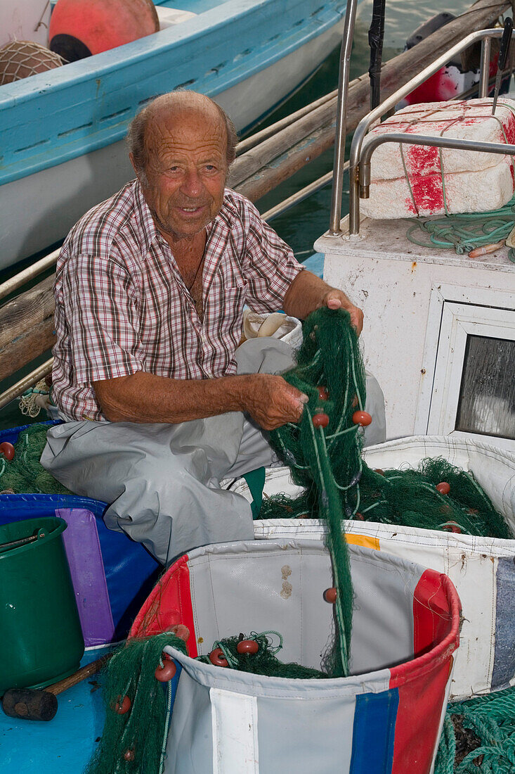 Fischerman cleaning fishing nets at the harbour, Agia Napa, South Cyprus, Cyprus
