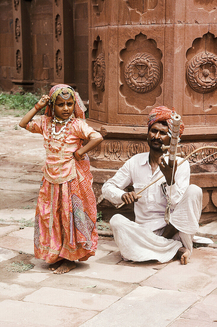 A man plays on a Rawanhatta while a little girl dances to the melody. Rajasthan, India