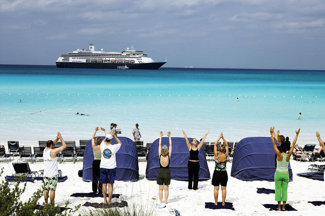 Aerobics class workout on the beach on Half Moon Cay with cruise ship in the background. Bahamas
