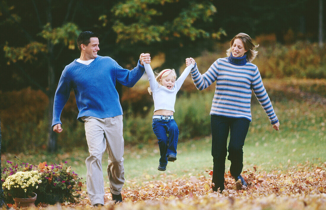 Mom and Dad running and holding up daughter