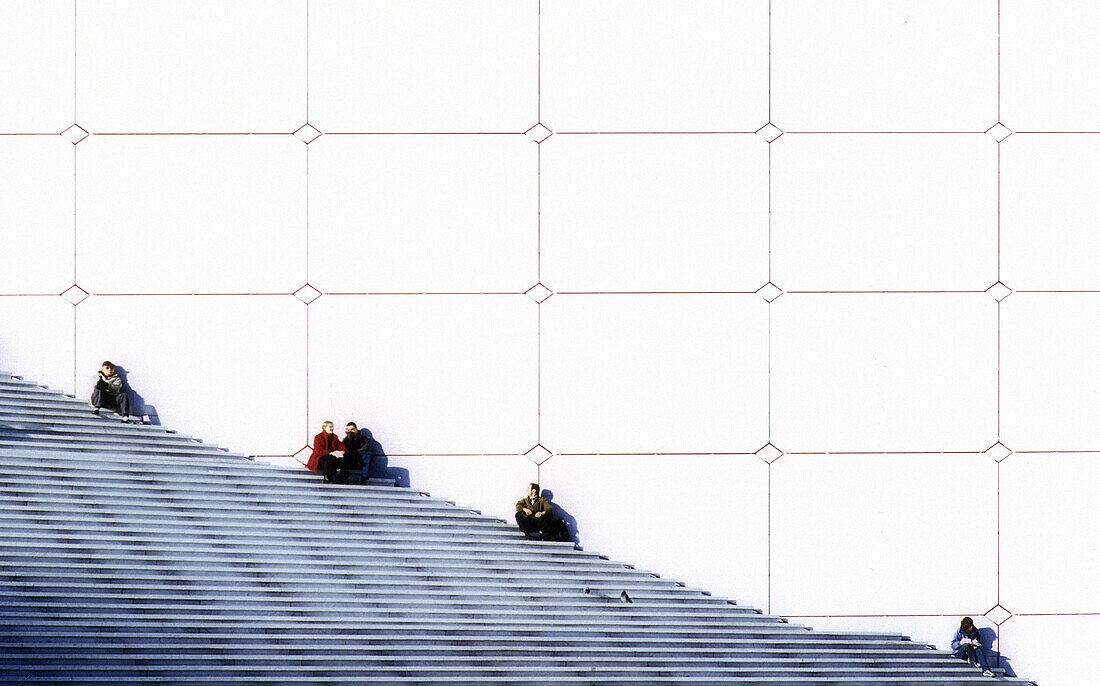 People sitting on entrance stairs to a building at La Defénse. Paris. France