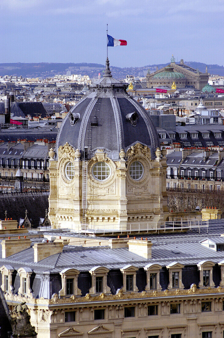 Aerial view of the domed Tribunal de Commerce with French flag and Garnier Opéra in the background. Paris. France